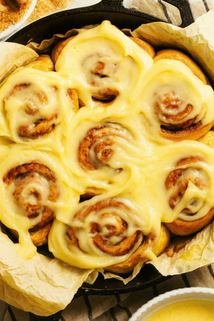 Freshly baked gluten free cinnamon rolls with vanilla icing in a skillet