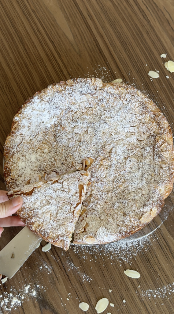 gluten free almond cake whole with powdered sugar and sliced almonds on top
